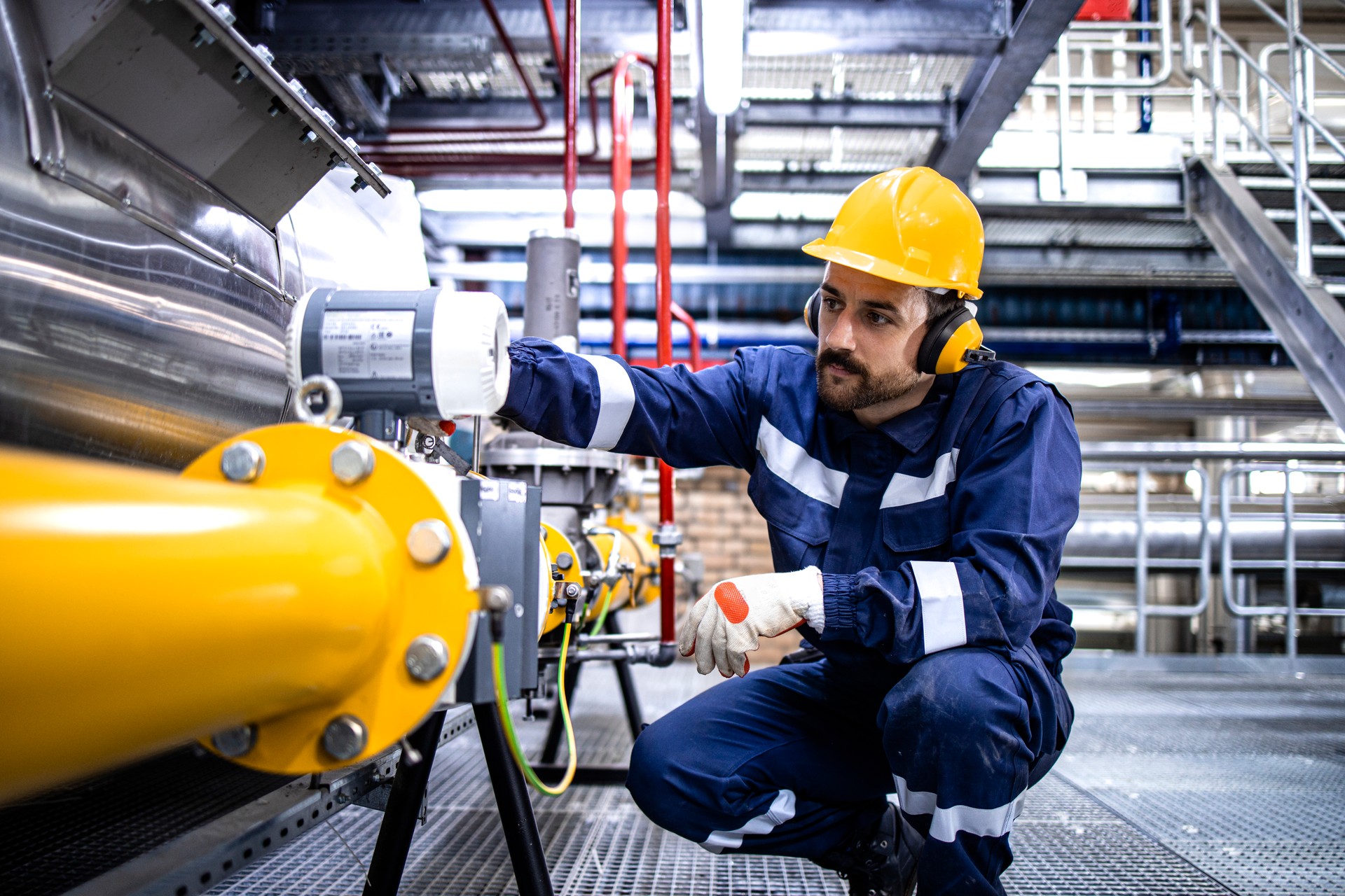 Trabalhador de colarinho azul da refinaria que está ao lado do gasoduto de GLP e verificando a produção ou distribuição de gás.